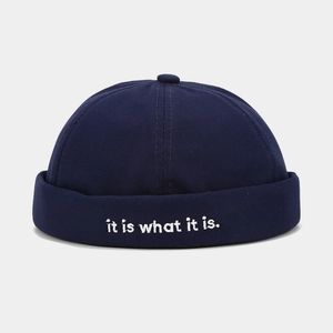 Detail of dark blue canvas docker hat featuring white embroidered it is what it is quote