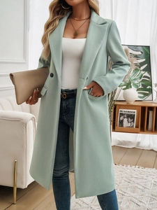 Detail of light green double-breasted long coat with elegant lapel and button closure