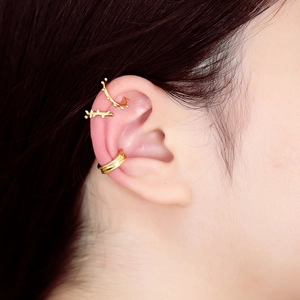 Close-up of stacked gold ear cuffs featuring textured hoops and a wide minimalist band