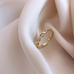 Close-up of gold twisted rope ring with shimmering zircon accents on silk fabric