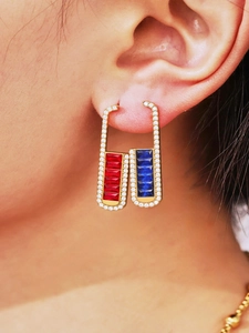 Detail of gold U-shaped earrings featuring red and blue square zircons with micro-pave crystals