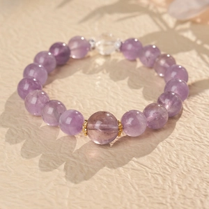 Macro shot of purple amethyst beaded bracelet with gold flower accents on a textured background