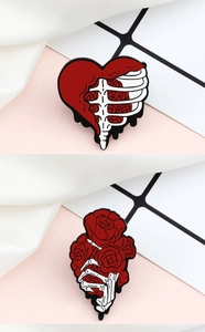Detail of enamel pins featuring a skull hand holding roses and a skeletal heart design
