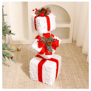 Close-up of three white snowy Christmas gift boxes with red velvet bows and pine cones