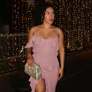 Detail of pink backless slit dress with ruffled edges and shiny evening clutch bag