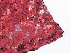 Detailed close-up of vibrant red sequins on mesh fabric for a sexy party dress