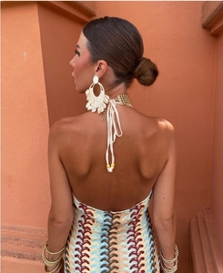 Detail of bohemian woven shell earrings with a metallic choker on a sunlit model