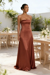 Detailed back view of a rust-brown satin backless formal dress in an outdoor setting