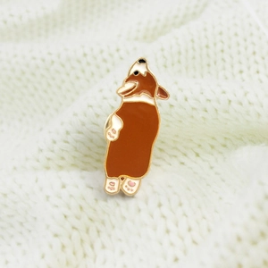 Detail of cute enamel Corgi brooch on white knit sweater with golden metal outlines