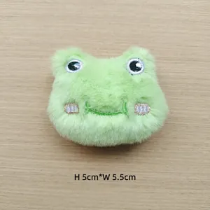 Close-up of a plush green frog head accessory featuring embroidered eyes and 5x5.5cm size