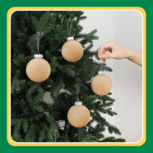 Close-up of four minimalist natural velvet Christmas balls hanging on green pine branches