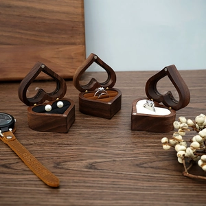 Macro view of heart-shaped walnut wood ring box with velvet lining on a wooden surface