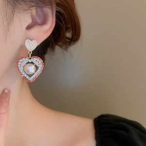 Vue détaillée des boucles d'oreilles cœur avec perles, base dorée et perles colorées