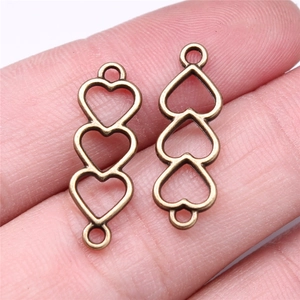 Close-up of three hollow heart connector charms in vintage bronze finish for DIY jewelry