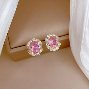 Macro view of gold-plated stud earrings featuring pink oval zircon and trapezoid accents