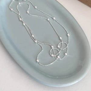 Dettaglio della collana S925 argento con perle quadrate su piatto in ceramica blu