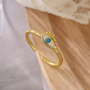 Close-up of golden Evil Eye open ring with blue enamel on a rustic wood surface