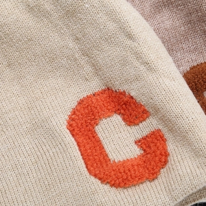 Chunky knit beanie featuring a fuzzy orange chenille C letter patch on beige fabric