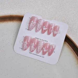 Detail of almond-shaped pink jelly press-on nails with white floral relief and pearls