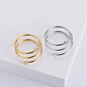 Close-up of spiral open rings in gold and silver finish with zircon stone accents