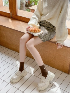 Detail of dark brown cotton crew socks with white heart embroidery worn with loafers
