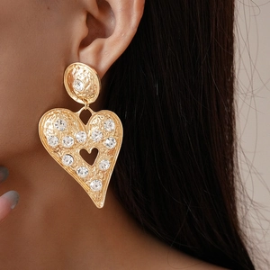 Détail de grandes boucles d'oreilles cœur doré avec cristaux sur un mannequin