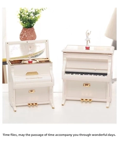 Detail of white piano music box with rotating ballerina and gold pedal accents