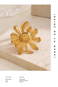 Détail d'une bague tournesol dorée avec texture fine sur socle en marbre travertin