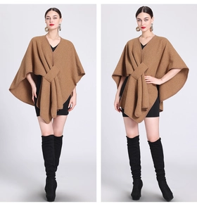 Detail of a brown knitted poncho cape featuring a stylish front tie design and cozy texture