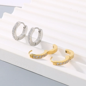 Close-up of gold and silver stainless steel huggie earrings with sparkling crystals