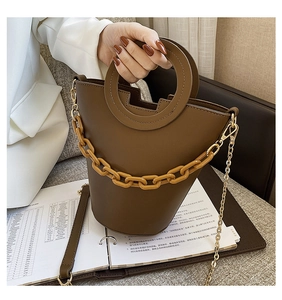 Brown leather bucket bag with round handle and thick yellow plastic chain detail