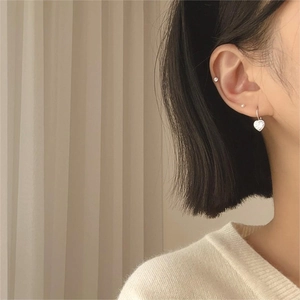 Detailed view of silver heart earrings with sparkling zircons worn by a model