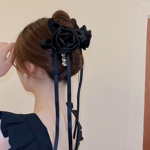 Détail d'une pince à cheveux rose en soie noire avec rubans et breloques en cristal