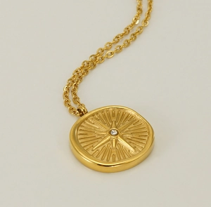 Detailed close-up of a gold starburst compass pendant necklace with center crystal stone