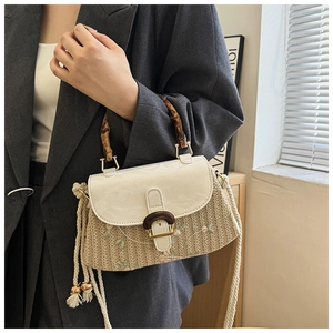 Detail showing natural bamboo handle and delicate floral embroidery on straw bag