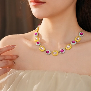 Close-up of vintage gold necklace with pink and yellow gemstones on model