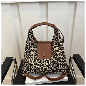Détail du sac cabas imprimé léopard avec rabat en cuir marron et sangles sur une chaise
