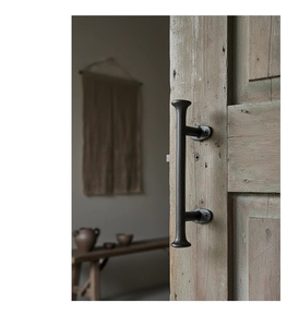 Détail macro d'une poignée de porte industrielle en fonte noire sur une porte en bois usé