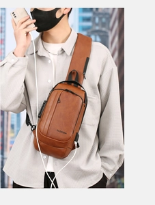Brown leather sling bag with USB port and anti-theft lock worn by a model in the city