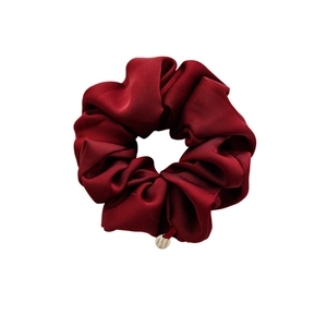 Premium burgundy satin scrunchie with a glossy finish and a round metal logo charm