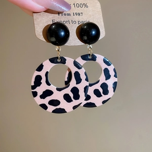 Detail of leopard print hoop earrings with black studs and gold rings on card packaging