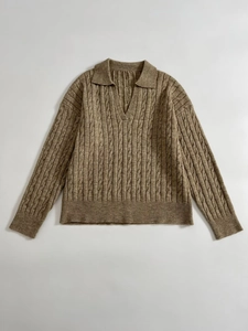 Detail of tan cable knit sweater featuring classic V-neck polo collar and ribbed cuffs