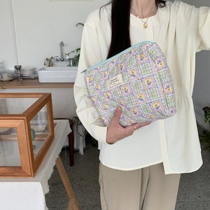 Handheld quilted floral makeup bag with blue lavender patterns and woven label details