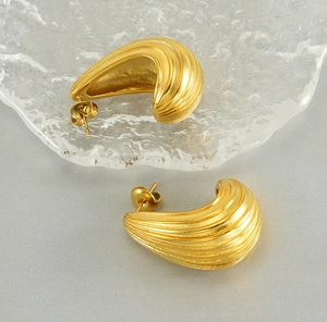 Detail view of 18K gold plated hollow C-shape earrings with textured wave stripe pattern