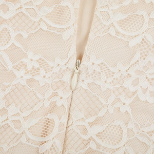 Detailed close-up of beige lace fabric with seamless invisible zipper and fine embroidery