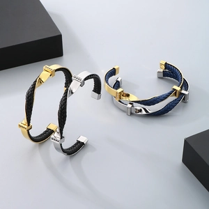 Detail of twisted titanium steel C-shape bangles with braided leather and zirconia inlay