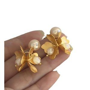 Elegant gold flower earrings with freshwater pearls shown held by hand for size reference