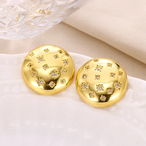 Elegant gold starburst stud earrings with white zircons on a textured metal surface