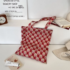 Detail view of red floral canvas tote bag with wide handles for daily commute usage