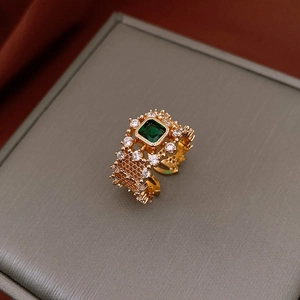 Détail macro d'une bague plaquée or avec zircon vert carré et anneau ajouré chic